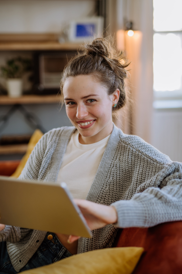 Young woman with digital tablet resting in the apartment.