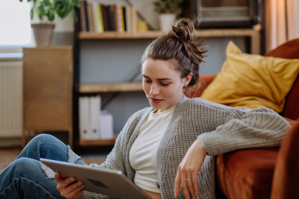 Young woman with digital tablet resting in the apartment.