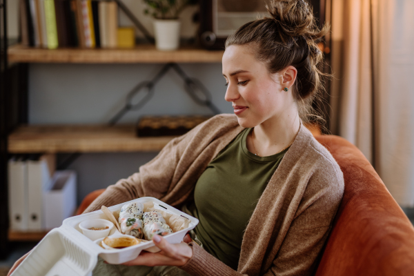 Young woman enjoying delivered food in the living room.