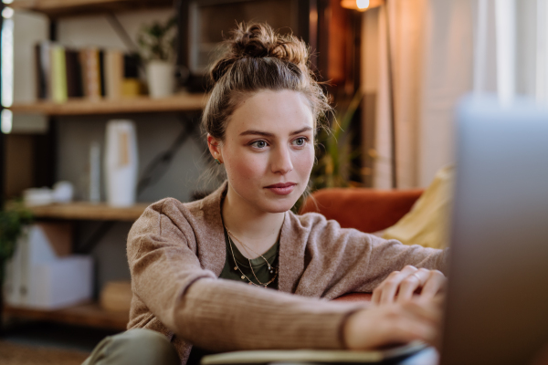 Young woman with laptop resting in the apartment.