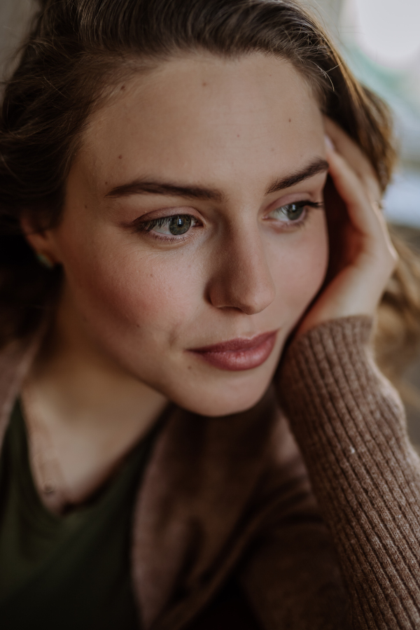 Portrait of young pensive woman, in the apartment.