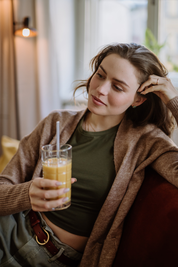 Young woman sitting on sofa with a drink.