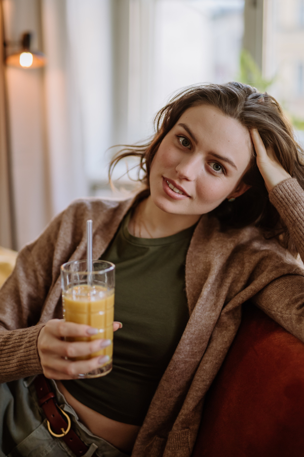 Young woman sitting on sofa with a drink.