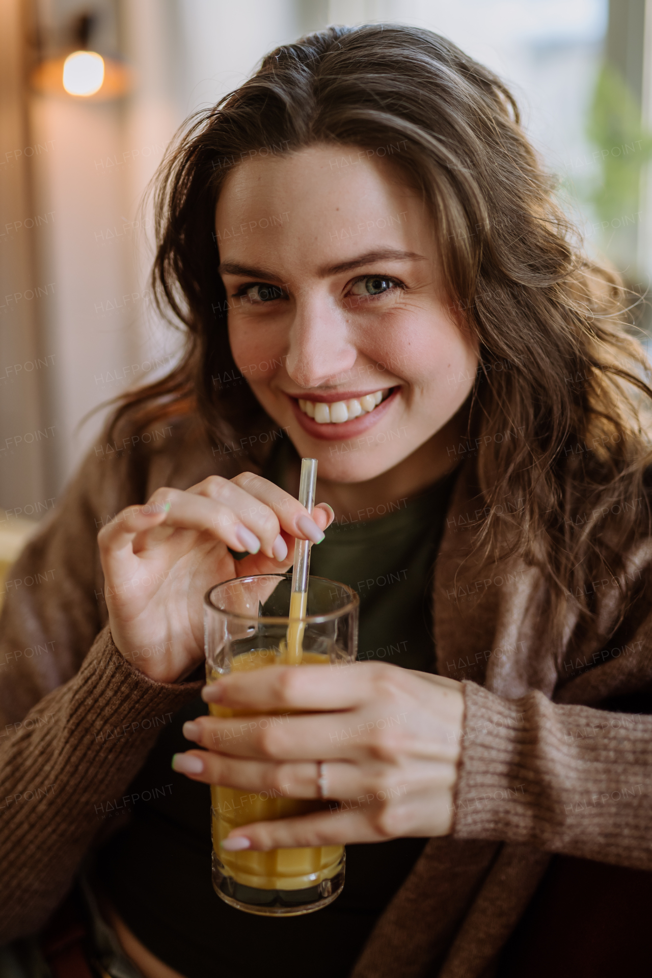 Young woman sitting on sofa with a drink.