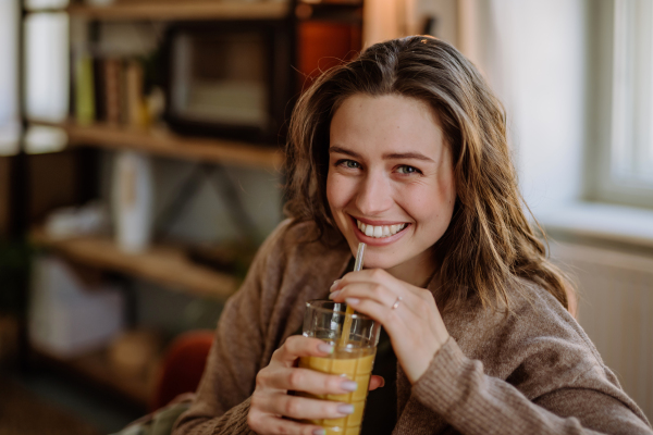 Young woman sitting on sofa with a drink.