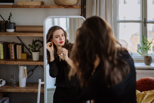 Young woman in elegant dress preparing for an evening, looking in a mirror.