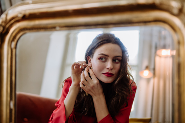 Young woman in elegant dress preparing for an evening, looking in a mirror.