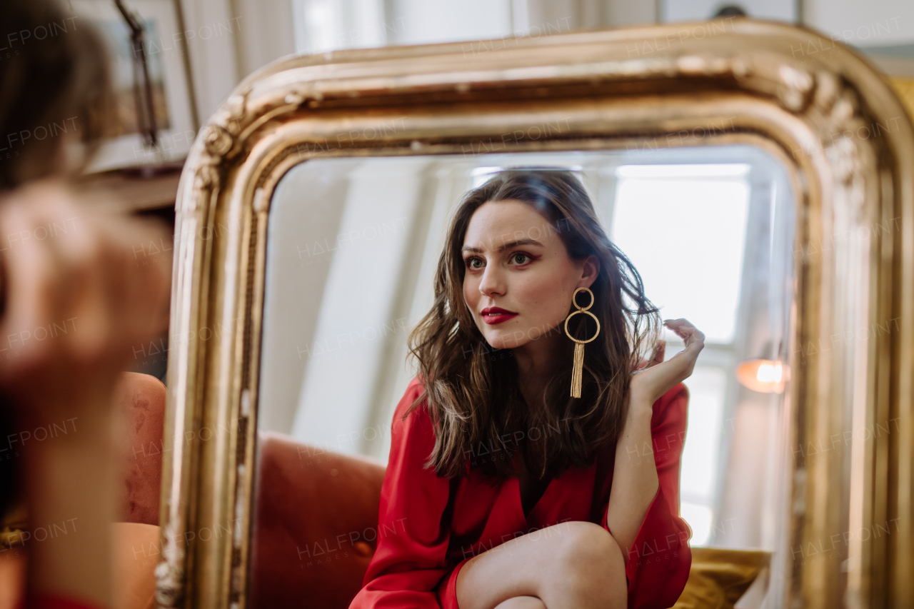 Young woman in elegant dress preparing for an evening, looking in a mirror.