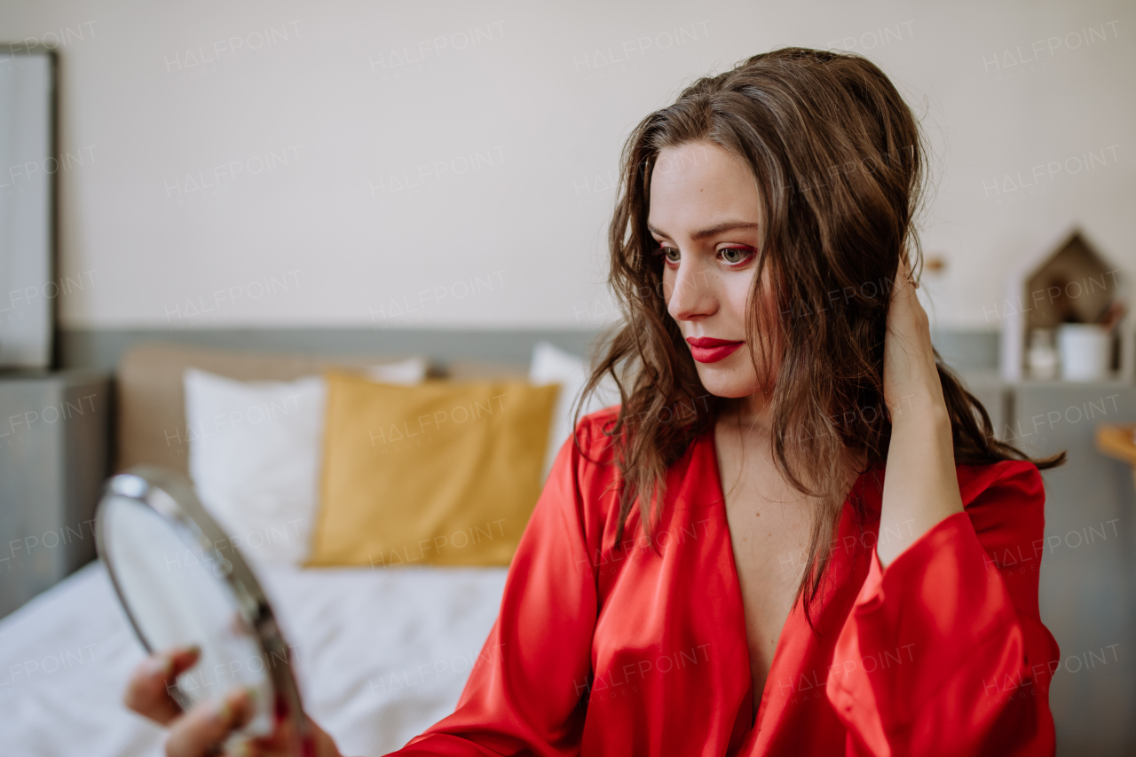 Young woman in elegant dress preparing for an evening, finishing her make up.