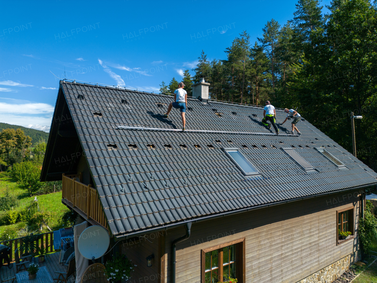 Men worker installing solar photovoltaic panels on a roof, alternative energy, saving resources and sustainable lifestyle concept.