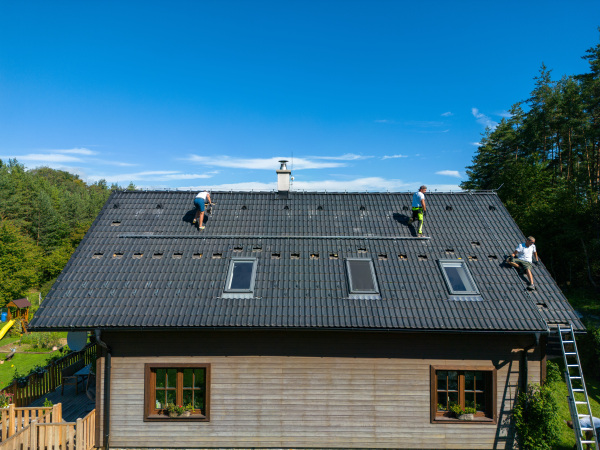 High angle view of men worker installing solar photovoltaic panels on a roof, alternative energy, saving resources and sustainable lifestyle concept.