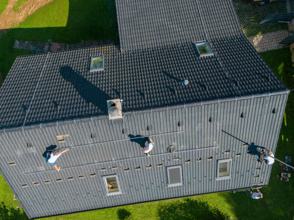 Men worker installing solar photovoltaic panels on a roof, alternative energy, saving resources and sustainable lifestyle concept.