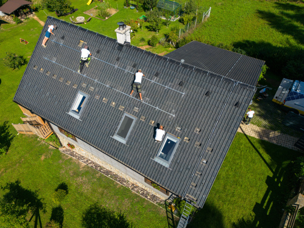 Men worker installing solar photovoltaic panels on a roof, alternative energy, saving resources and sustainable lifestyle concept.