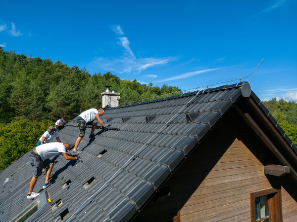 Men worker installing solar photovoltaic panels on a roof, alternative energy, saving resources and sustainable lifestyle concept.