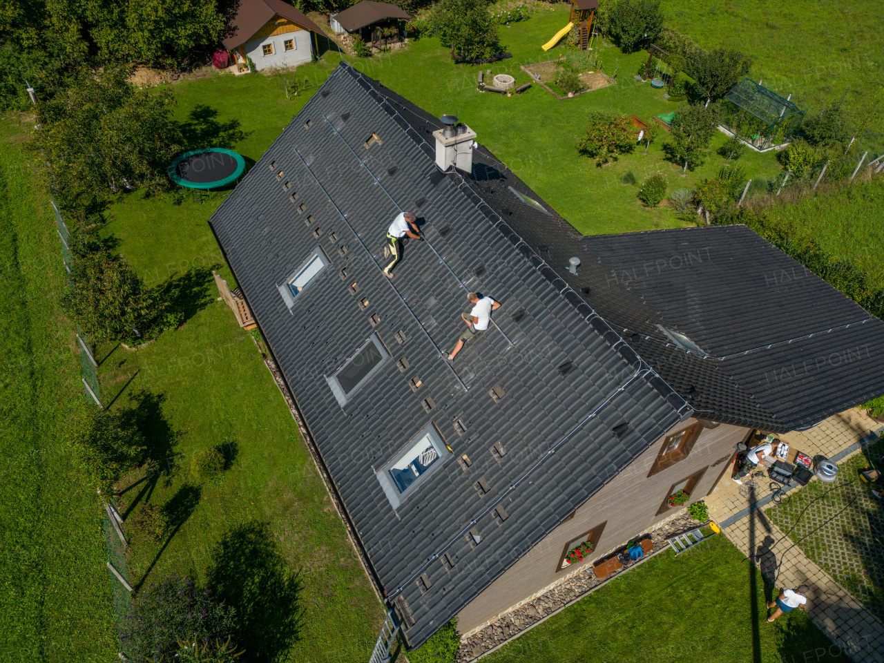 High angle view of men worker installing solar photovoltaic panels on a roof, alternative energy, saving resources and sustainable lifestyle concept.