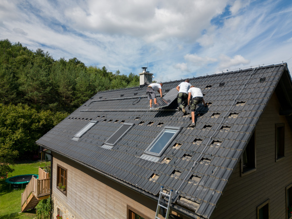 Men worker installing solar photovoltaic panels on a roof, alternative energy, saving resources and sustainable lifestyle concept.