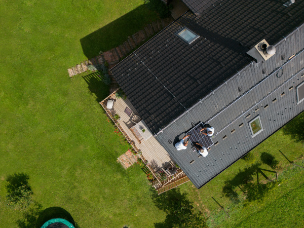 Men worker installing solar photovoltaic panels on a roof, alternative energy, saving resources and sustainable lifestyle concept. Top view.