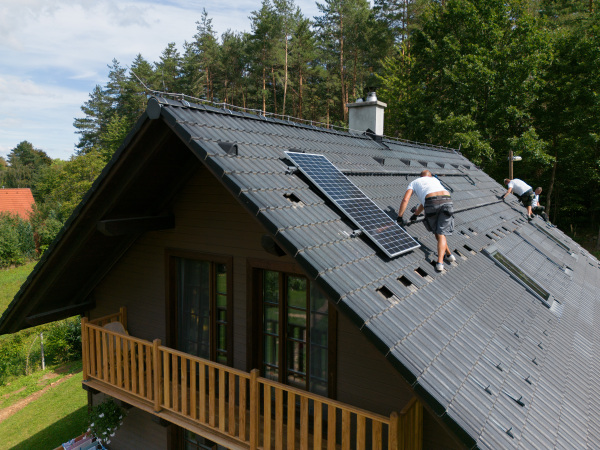 Men worker installing solar photovoltaic panels on a roof, alternative energy, saving resources and sustainable lifestyle concept.