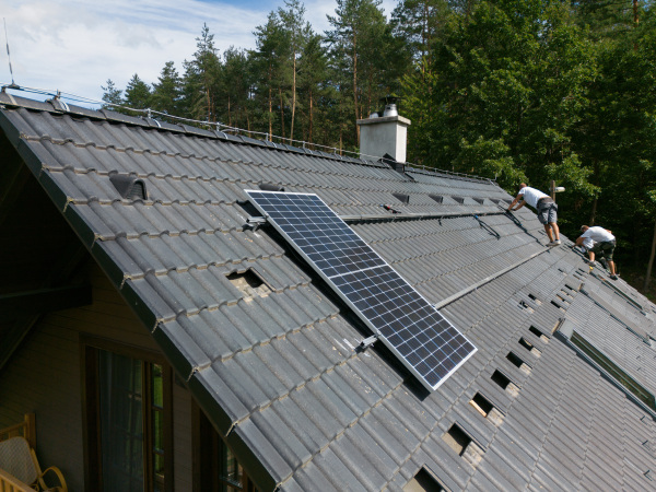 Men worker installing solar photovoltaic panels on a roof, alternative energy, saving resources and sustainable lifestyle concept.