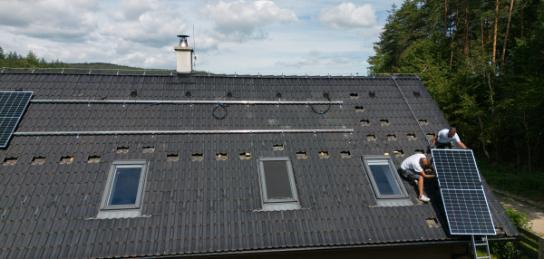 Men worker installing solar photovoltaic panels on a roof, alternative energy, saving resources and sustainable lifestyle concept.