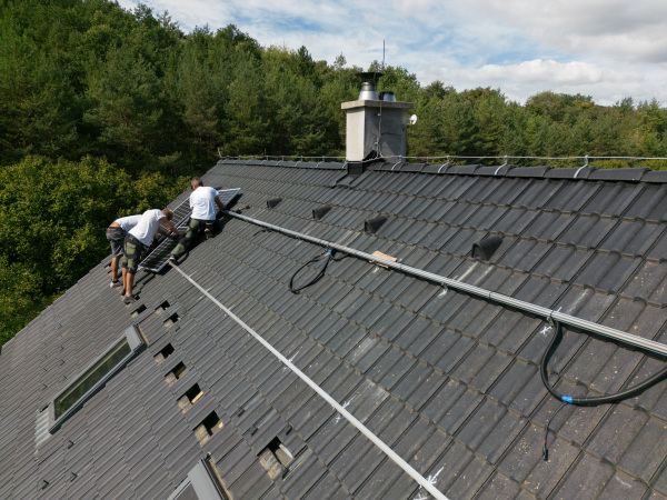 Men worker installing solar photovoltaic panels on a roof, alternative energy, saving resources and sustainable lifestyle concept.