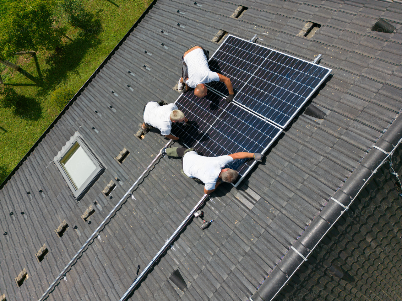 High angle view of men worker installing solar photovoltaic panels on a roof, alternative energy, saving resources and sustainable lifestyle concept.