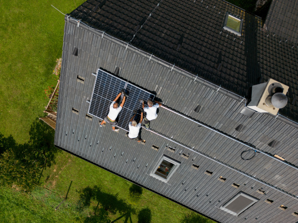 Top view of men worker installing solar photovoltaic panels on a roof, alternative energy, saving resources and sustainable lifestyle concept.