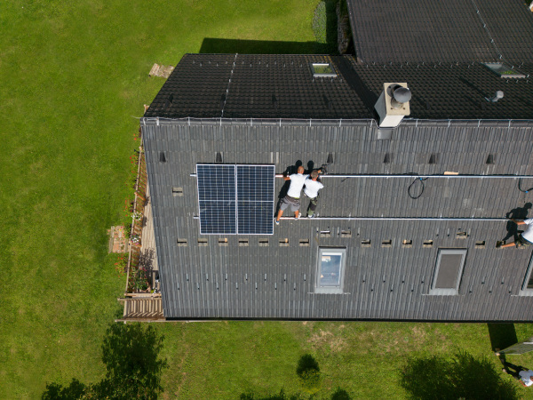 Men worker installing solar photovoltaic panels on a roof, alternative energy, saving resources and sustainable lifestyle concept.