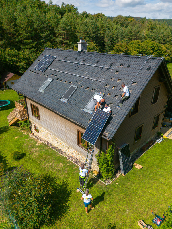 High angle view of men worker installing solar photovoltaic panels on a roof, alternative energy, saving resources and sustainable lifestyle concept.