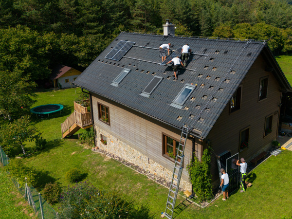 High angle view of men worker installing solar photovoltaic panels on a roof, alternative energy, saving resources and sustainable lifestyle concept.