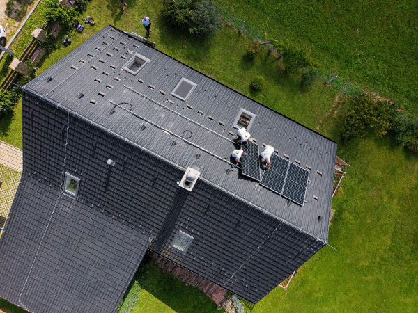 Top view of men worker installing solar photovoltaic panels on a roof, alternative energy, saving resources and sustainable lifestyle concept.