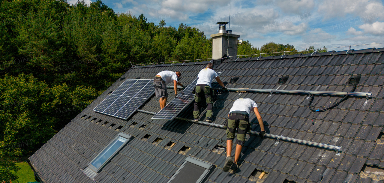 Men worker installing solar photovoltaic panels on a roof, alternative energy, saving resources and sustainable lifestyle concept.