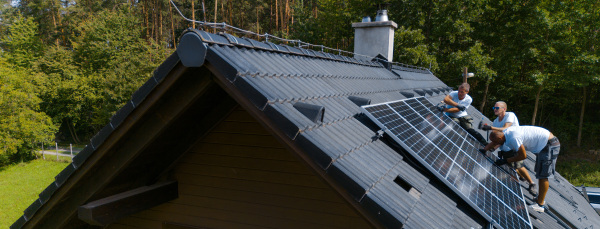 Men worker installing solar photovoltaic panels on a roof, alternative energy, saving resources and sustainable lifestyle concept.