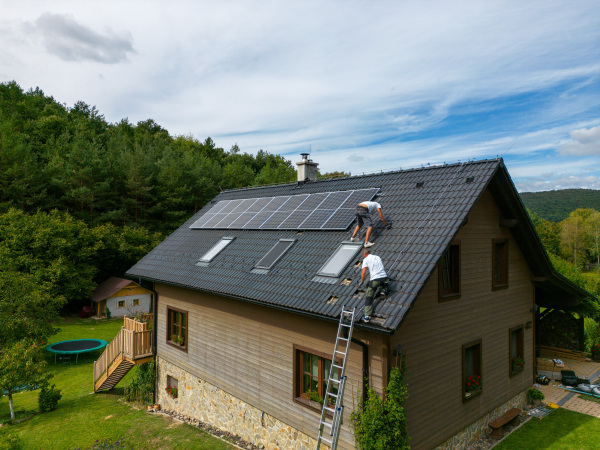 Men worker installing solar photovoltaic panels on a roof, alternative energy, saving resources and sustainable lifestyle concept.