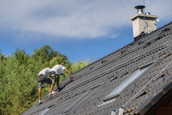 Men worker installing solar photovoltaic panels on a roof, alternative energy, saving resources and sustainable lifestyle concept.