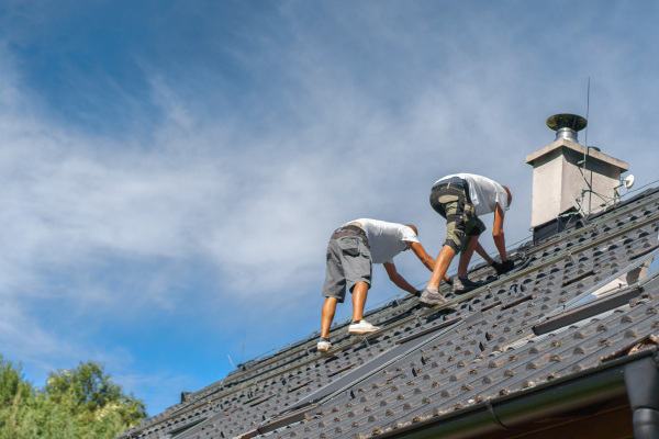 Men worker installing solar photovoltaic panels on a roof, alternative energy, saving resources and sustainable lifestyle concept.