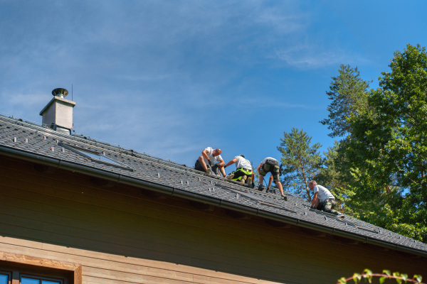 Men worker installing solar photovoltaic panels on a roof, alternative energy, saving resources and sustainable lifestyle concept.