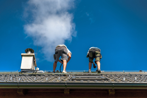 Men worker installing solar photovoltaic panels on a roof, alternative energy, saving resources and sustainable lifestyle concept.