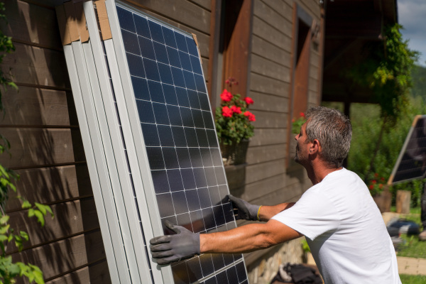 Mature man worker carrying a solar panel for installing.