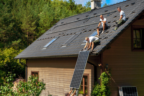 Men worker installing solar photovoltaic panels on a roof, alternative energy, saving resources and sustainable lifestyle concept.