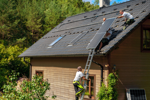 Men worker installing solar photovoltaic panels on a roof, alternative energy, saving resources and sustainable lifestyle concept.