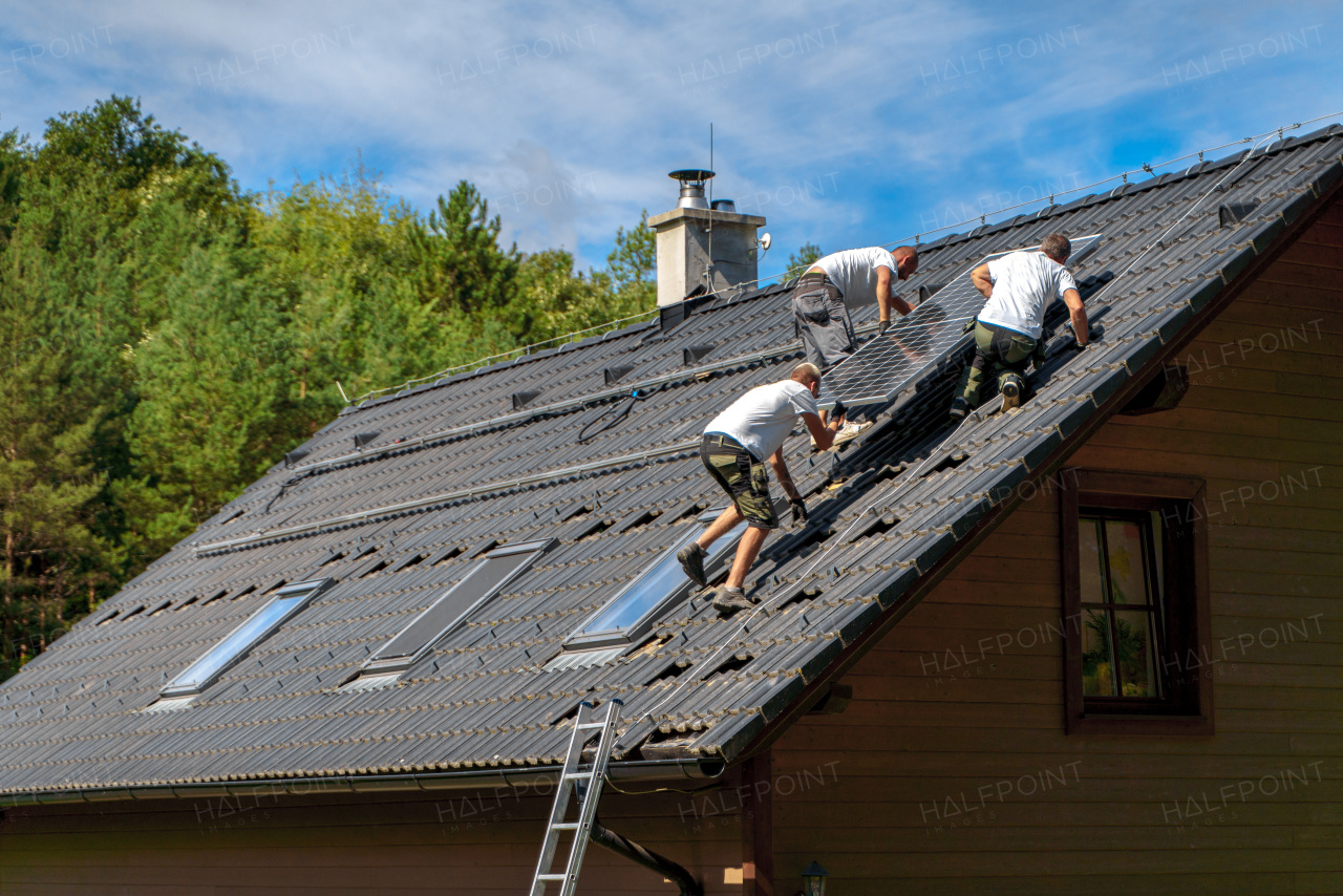 Men worker installing solar photovoltaic panels on a roof, alternative energy, saving resources and sustainable lifestyle concept.