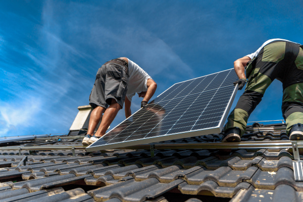 Men worker installing solar photovoltaic panels on a roof, alternative energy, saving resources and sustainable lifestyle concept.