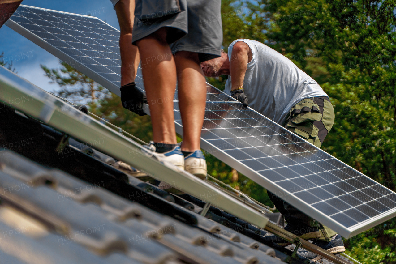 Men worker installing solar photovoltaic panels on a roof, alternative energy, saving resources and sustainable lifestyle concept.