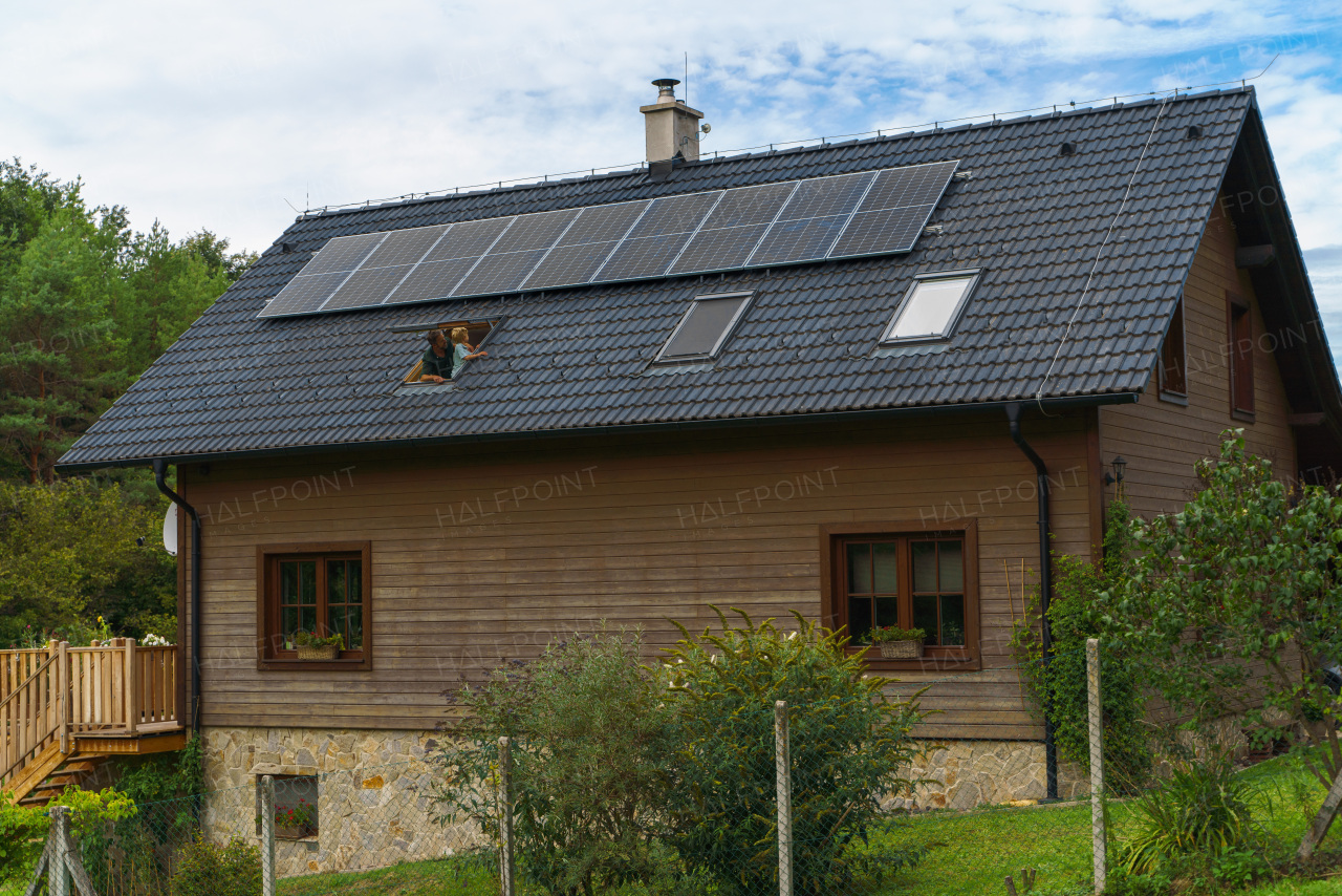 Father with his little son looking from a skylight windows at solar panels on their roof. Alternative energy, saving resources and sustainable lifestyle concept.