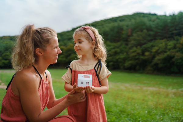 Little girl with her father holding paper model of house with the solar panels.Alternative energy, saving resources and sustainable lifestyle concept.