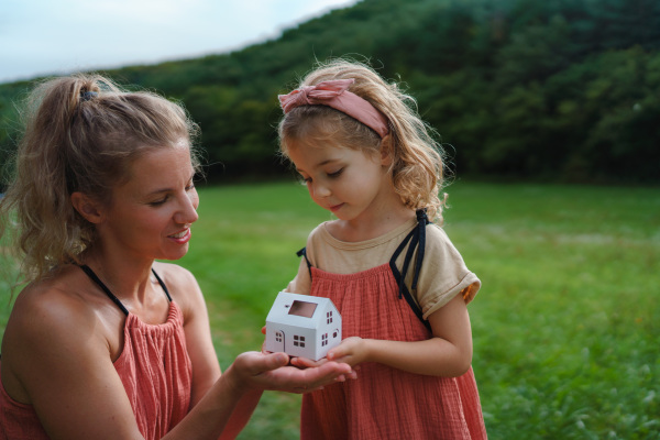 Little girl with her father holding paper model of house with the solar panels.Alternative energy, saving resources and sustainable lifestyle concept.