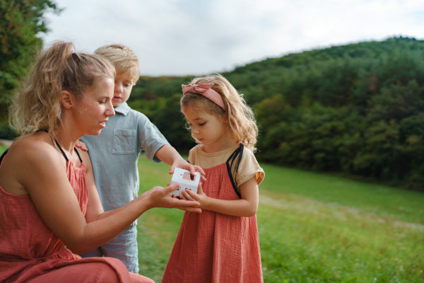 Little girl with her brother and mother holding and playing with paper model of house with a solar panels.Alternative energy, saving resources and sustainable lifestyle concept.