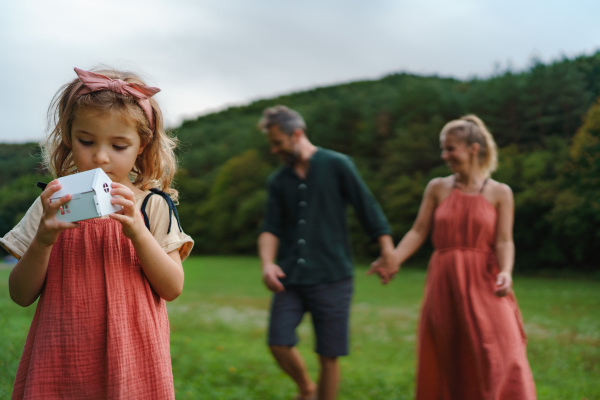 Little girl with holding and playing with paper model of house with the solar panels.Alternative energy, saving resources and sustainable lifestyle concept.