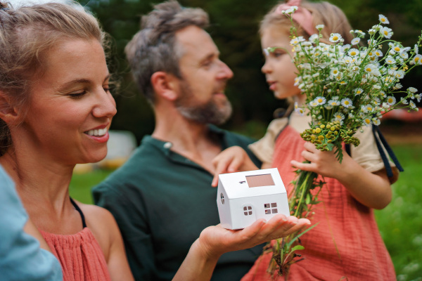 Close up of young mother holding paper model of house with the solar panels.Alternative energy, saving resources and sustainable lifestyle concept.